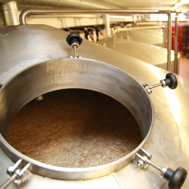A large stainless steel tank filled with liquid in a brewery.